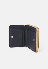 Portafoglio in pelle blu navy con zip dorata, dotato di molteplici scomparti per carte e chiusura a scatto, texture liscia e design minimalista.