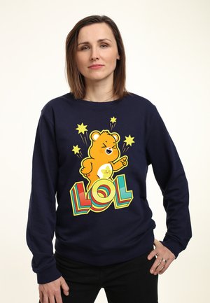 Sweat-shirt bleu marine avec un graphique de ours en dessin animé dans une gamme de couleurs jaunes et le mot "LOL" en lettres colorées et en gras.