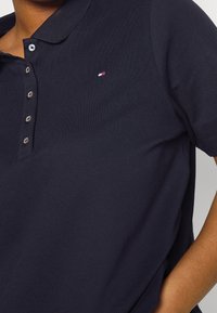 Mörkblå polo skjorta gjord av strukturerad tyg, med en klassisk krage och tre knappar samt en liten logotyp på bröstet.