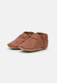 Pantofi de bebeluși din piele maro cu talpă moale, având o suprafață texturată și curea cu velcro pentru o fixare sigură, proiectați într-un stil minimalist.