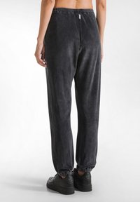 Graue Velvet-Sweatpants mit elastischen Bündchen und Bund. Sie verfügen über eine glatte Textur und eine lockere Passform, die sich gut für lässige Kleidung eignet.