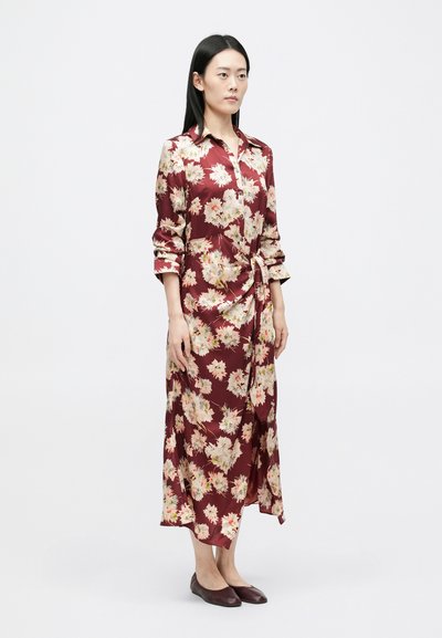 Marońska sukienka koszulowa z długimi rękawami, przewiązywana w talii, o luźnym kroju. Wzbogacona dużymi kremowymi i żółtymi wzorami kwiatowymi.