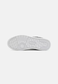 White rubber outsole with textured grip pattern and circular detailing; features "Lacoste" logo embossed on the side.