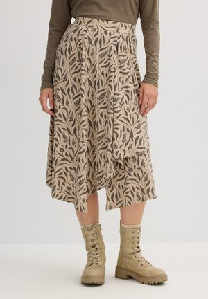 Falda beige con un diseño estampado de motivos de hojas, con pliegues y un estilo fluido. Combinada con botas de combate color marrón claro con cordones.