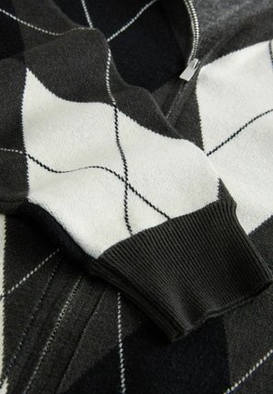 Schwarz-weißer Pullover im Argyle-Muster mit leichter Textur, Reißverschluss und gerippten Bündchen, ausgestattet mit kontrastierenden Stichdetails.