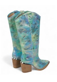Botas de vaquera con un acabado brillante en tonos azul-verde, punta afilada, costuras decorativas y un tacón de madera apilada con acentos metálicos.