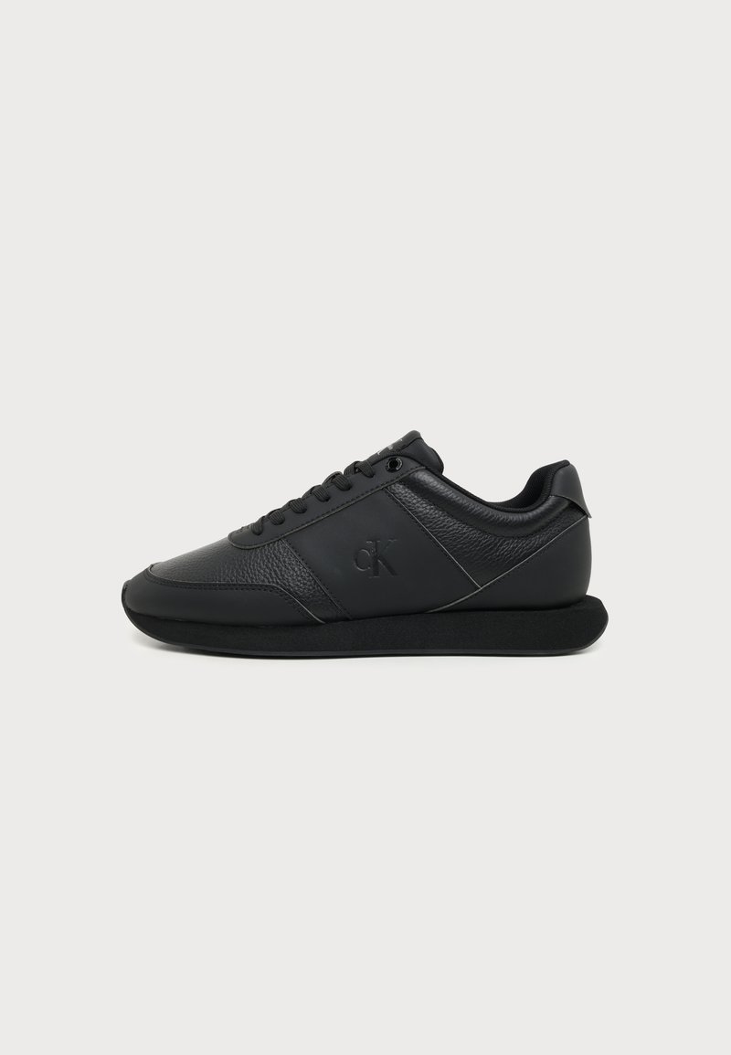 Μαύρο δερμάτινο sneaker χαμηλού προφίλ με κορδόνια, υφασμένους και λείους πίνακες, επίπεδη σόλα και διακριτικό λογότυπο "cK" στο πλάι.