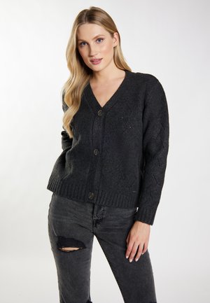 Dunkelgrauer gestrickter Cardigan mit V-Ausschnitt, Frontknöpfen, Strukturmuster und geripptem Saum, kombiniert mit schwarzen, zerrissenen Jeans.