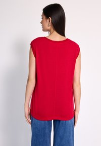 Top rojo sin mangas con escote redondo y un corte relajado. Material suave, textura lisa. Presenta un diseño simple y limpio, sin adornos.