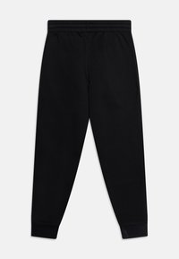 Pantaloni de trening negri dintr-un amestec de bumbac neted, având un brâu elastic și manșete strâmte la glezne. Fără buzunare sau detalii suplimentare.