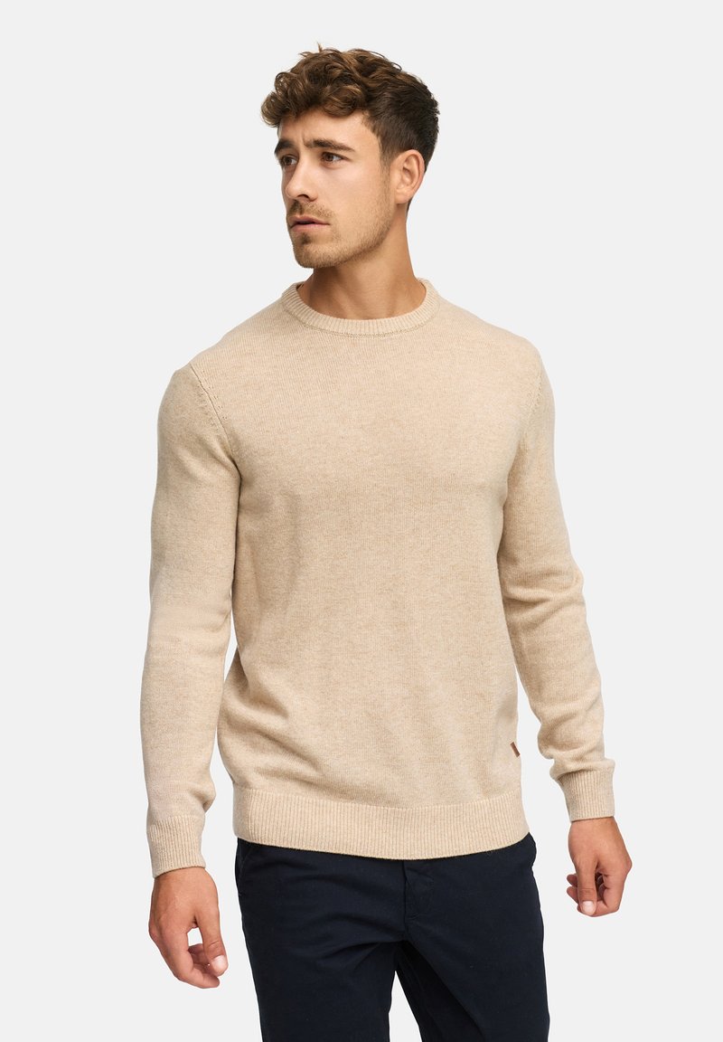 Suéter de punto beige con cuello redondo y puños y dobladillo acanalados. Hecho de material suave con una textura sutil.