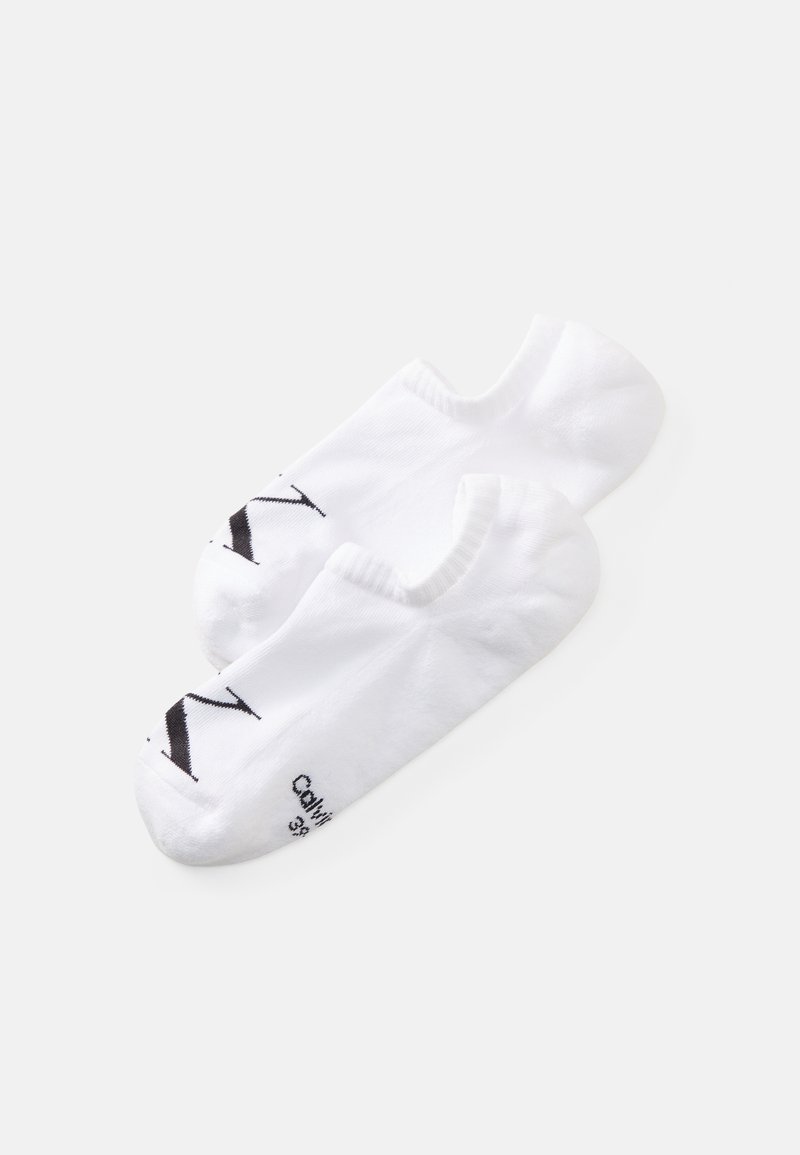 Hvite anklestrømper laget av myk stoff, med en svart logo og tekst på sålen. Enkel design med lav klipp.