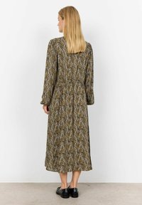 Langemouwige jurk in bruin en groen bloemenpatroon, met een gathered taille, midi-lengte, van zachte stof, gecombineerd met zwarte schoenen.