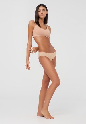Bralette wireless color nudo e bikini coordinato. Tessuto morbido e liscio con un design senza cuciture. Stile minimalista senza hardware visibile.