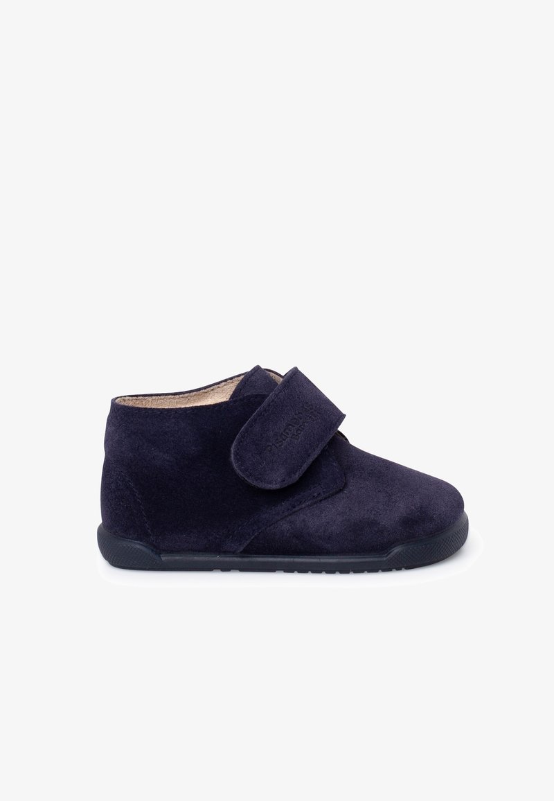Chaussure pour enfant en daim bleu marine avec une bride à Velcro, texture douce, bout arrondi et semelle en caoutchouc pour l'adhérence et le confort.