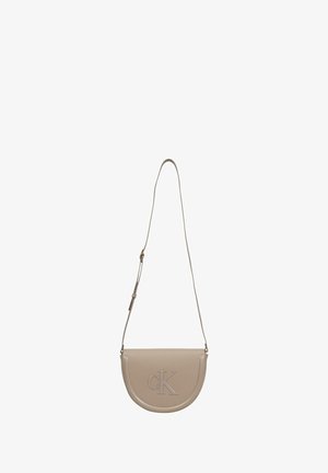 Beige læder crossover-taske med en buet form, med en forhøjet "CK"-logo, justerbar rem og glat tekstur.