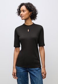 Sort kortærmet top med rund halsudskæring og en lille nøglehul detalje i midten. Stoffet ser glat og strækbart ud.