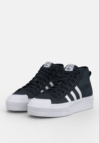 Scarpe da ginnastica alte con tomaia in tela blu scuro, punta in gomma bianca e tre strisce bianche sui lati. Suola bianca texturizzata.