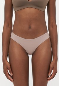 Beige nylon bikini briefs with a smooth, stretchy texture. Low-rise design with thin side straps. No visible patterns or additional embellishments.