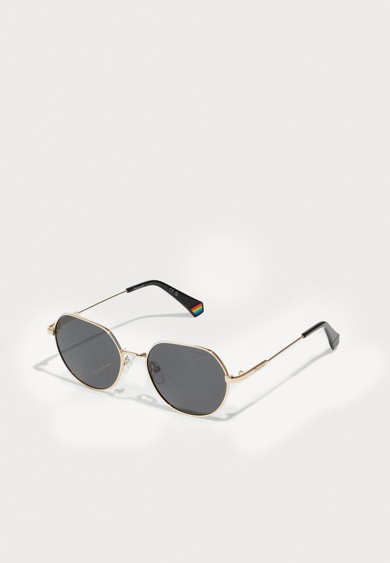 Gold metal sunglasses with gray lenses, an octagonal shape, thin temples, and a multicolored striped detail on the inner arm.
