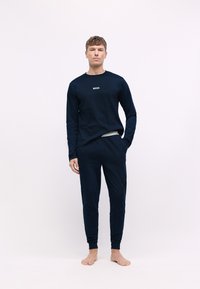 Camisa de manga larga azul marino con el logo "BOSS" y pantalones de chándal a juego; tela suave, diseño ajustado, puños elásticos y cintura elástica.