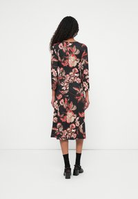 Zwarte jurk met bloemenprint en driekwartmouwen, voorzien van grote rode en beige bloemenpatronen, met een middellange snit en een luchtige textuur.
