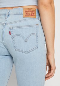 Light blue denim jeans with a classic design, featuring two back pockets, a leather label, and signature red tab on the side.