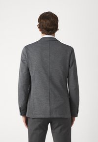 Blazer grigio con motivo, colletto a revers, sfiocco posteriore singolo e bottoni neri. Realizzato in un tessuto texturizzato, design aderente.