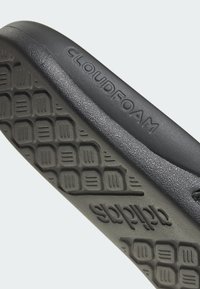 Semelle noire rembourrée avec une texture adhérente et le nom de marque "CLOUDFOAM" en relief. Design élégant, matériau durable et détails de motifs subtils.