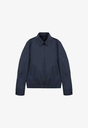 Chaqueta azul marino con cremallera, cuello de punta, dos bolsillos frontales, mangas largas con puños abotonados y cinturilla elástica.