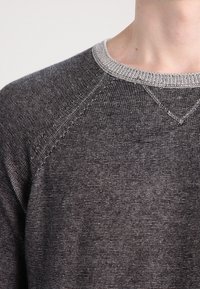 Szary sweter z okrągłym dekoltem, z teksturowanym wzorem i kontrastowym, jasnoszarym kołnierzem. Posiada rękawy raglanowe oraz ściągacze.