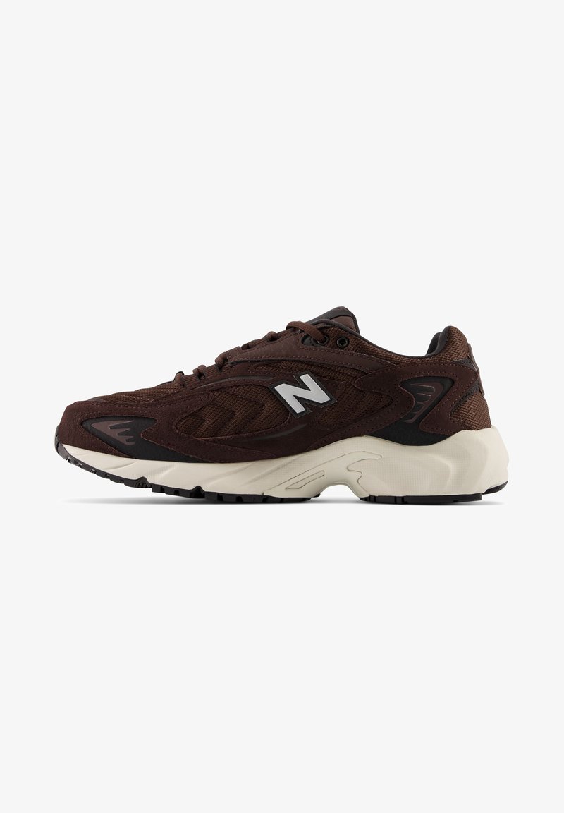 Baskets de sport marron foncé avec semelle blanche, dessus en mesh et en daim, fermeture à lacets, avec un logo blanc "N" sur le côté.