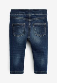 Jeans iz temno modrega denima z gladko teksturo, ki imajo dve zadnji žep in kontrastno šivanje. Oblikovanje do gležnjev.