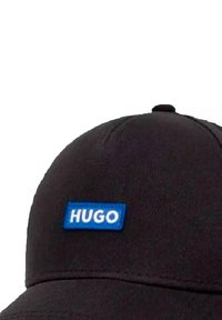 Schwarze Kappe mit strukturierter Form, die ein blaues rechteckiges Patch mit "HUGO" in weißem Text zeigt. Glatte Stoffoberfläche und gestickte Details.