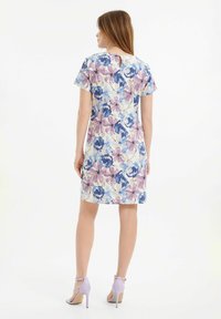 Kwiatowa sukienka z jasnobeżowym tłem i niebieskimi oraz fioletowymi kwiatami, krótkie rękawy oraz detal w kształcie dziurki z tyłu.