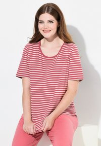 Camiseta de rayas rojas y blancas con mangas cortas y cuello redondo, combinada con pantalones rosa claro. Textura de tela suave.
