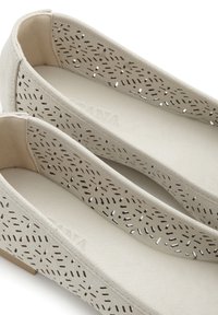 Helle graue Ballerinas aus perforiertem Material mit einer Innenauskleidung. Verfügt über eine flache Sohle und eine abgerundete Zehenpartie. Einfaches, minimalistisches Design.