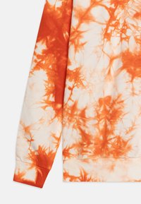 Orange and cream tie-dye sweatshirt with ribbed cuffs and hem. The fabric is soft, featuring a swirling pattern of blended colors.