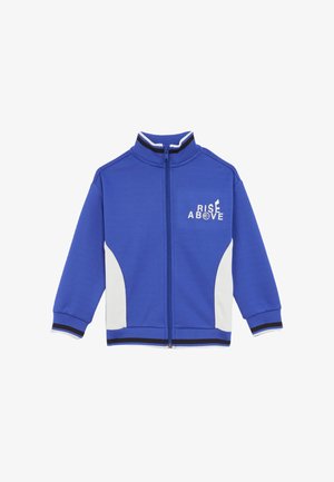 Giacca sportiva blu con colletto alto, pannelli laterali bianchi e dettagli a righe bianche e nere. Presenta la scritta "RISE ABOVE" stampata sul davanti.