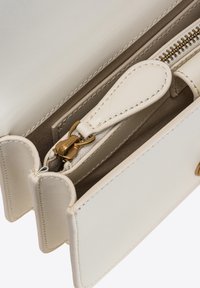 Portafoglio bianco in pelle con hardware dorato. Presenta un compartimento con zip, diversi scomparti per carte e un interno testurizzato. Design pulito, stile minimalista.