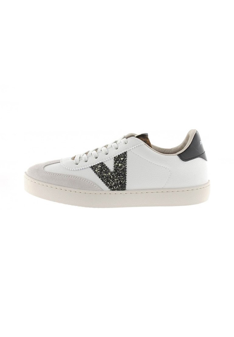 Baskets en cuir blanc avec un bout en daim gris, présentant un grand design en paillettes noires en forme de "V" sur le côté et un accent de talon noir.