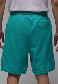 Turkises atletiske shorts lavet af bomuldsblanding. Har en elastisk talje og en baglomme med diagonal accentstik.