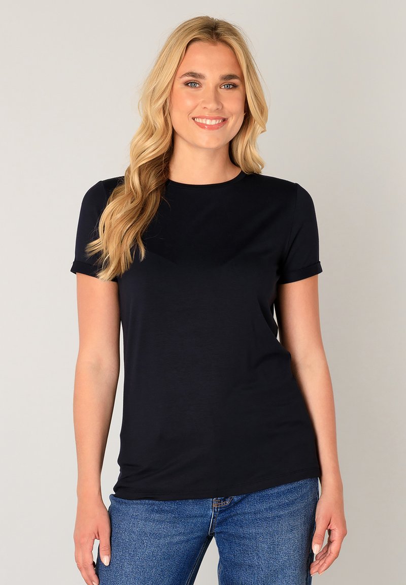 Donkerblauw T-shirt met korte mouwen van een zachte, gladde stof met een ronde hals. Gecombineerd met casual blauwe jeans. Minimalistisch ontwerp, zonder patronen.