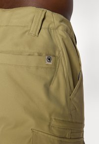 Khaki cargo šortky s voľným strihom, viacerými vreckami, našitou etiketou a hladkou textúrou látky.