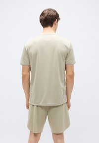 Camisola bege clara de manga curta com decote redondo, tecido texturizado e costura lateral, combinada com calções a condizer.