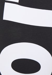 Svart tyg med stora vita grafiska former, inklusive en cirkel och ett streck, med en mjuk och slät yta. Texturerad finish i högkontrastdesign.