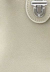 Beige Lederhandtasche mit strukturierter Oberfläche, ausgestattet mit einem silbernen Metallverschluss und Stickdetails entlang der Kante.