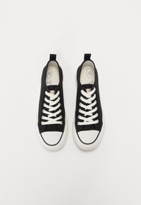 Sneakers neri in tela con lacci bianchi, punta in gomma bianca e tab posteriore. Suola piatta, design minimalista e dettagli di cucitura a contrasto.