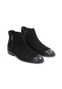 Las botas de tobillo de gamuza negra cuentan con una puntera de cuero negro liso, cremalleras laterales y un tacón rectangular bajo. Diseño simple y elegante.