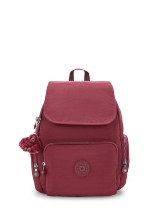 Burgundy backpack with a fold-over flap, front zip pocket, rounded logo, and a plush monkey keychain attached to the zipper.